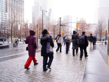 Group of UM students walking in NYC, after it rained, wearing coats. Close to the Twin Towers memorial.